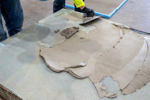Concrete resurfacer troweled onto a worn slab for a smooth patch.
